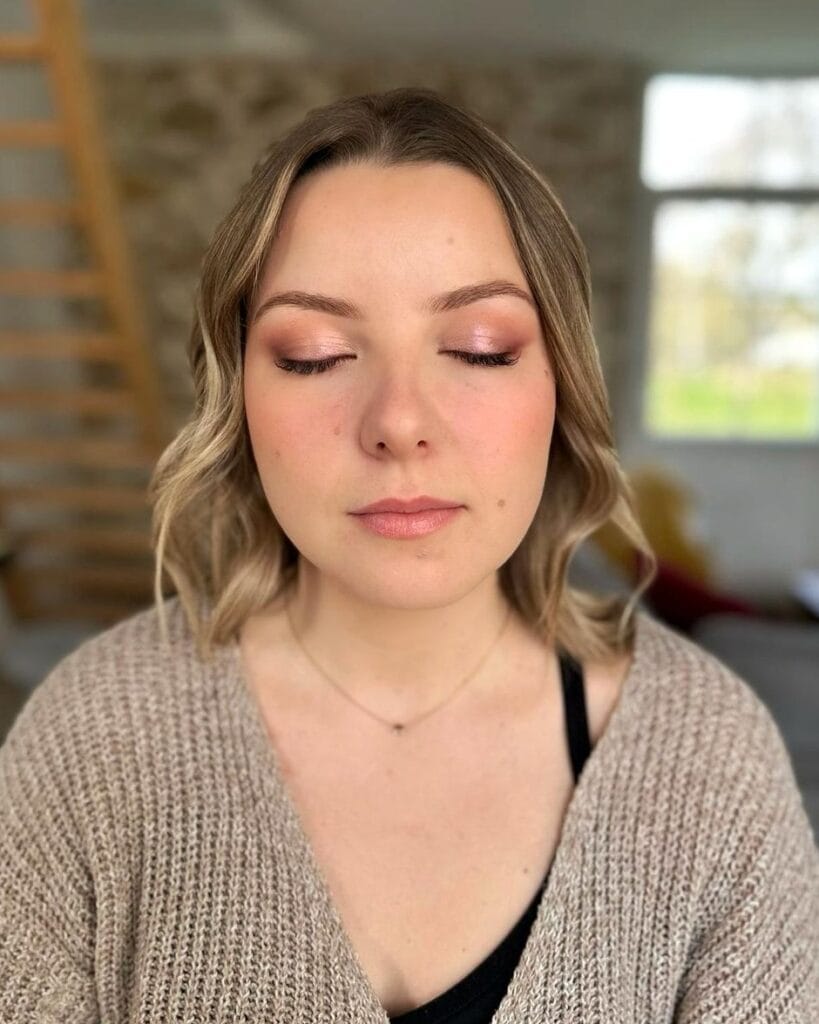 Femme portant un maquillage de soirée naturel avec fards rosés lumineux et teint frais.