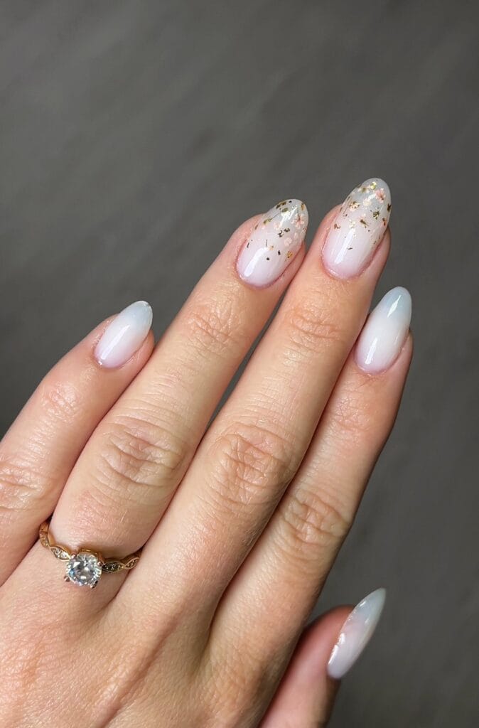 Ongles fleurs incrustées et feuilles d'or sur gel blanc laiteux