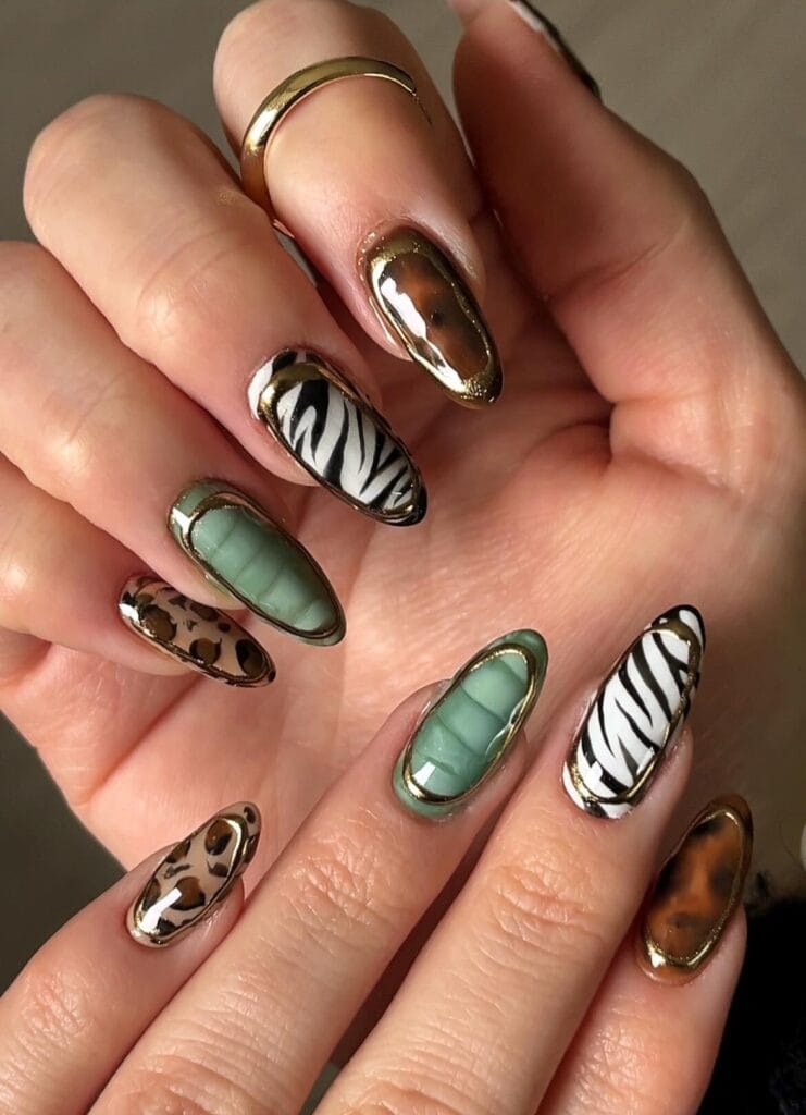 Pose d’ongles amande avec nail art zèbre, léopard et effet écaille marron avec contours dorés chrome.