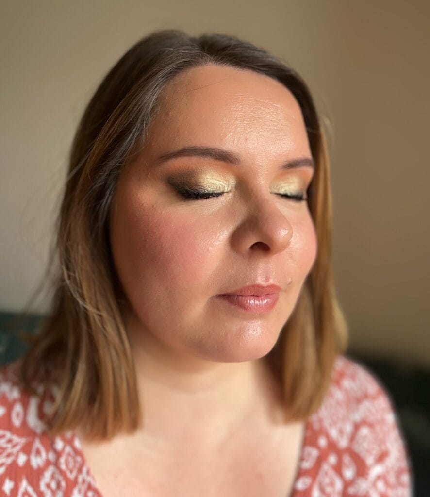 Femme portant un maquillage sophistiqué avec yeux dorés lumineux et smoky brun intense.