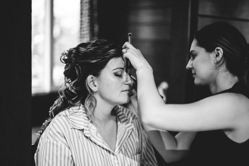 Maquilleuse professionnelle réalisant le maquillage d’une mariée pendant les préparatifs de mariage.